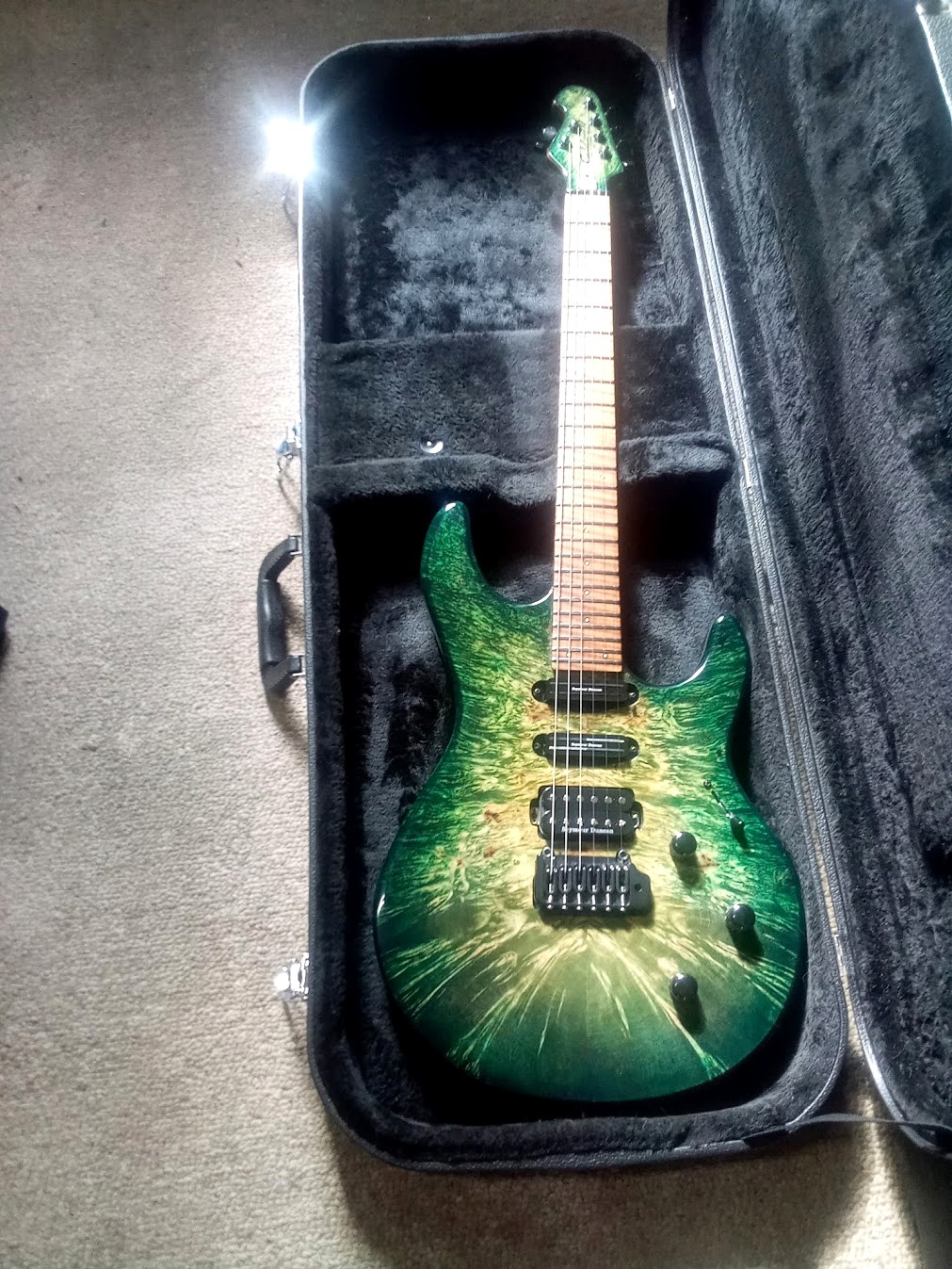 Green custom carved-top Caldwell guitar in a black case