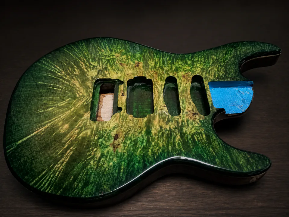 Green burst figured guitar body in progress on a professional studio background